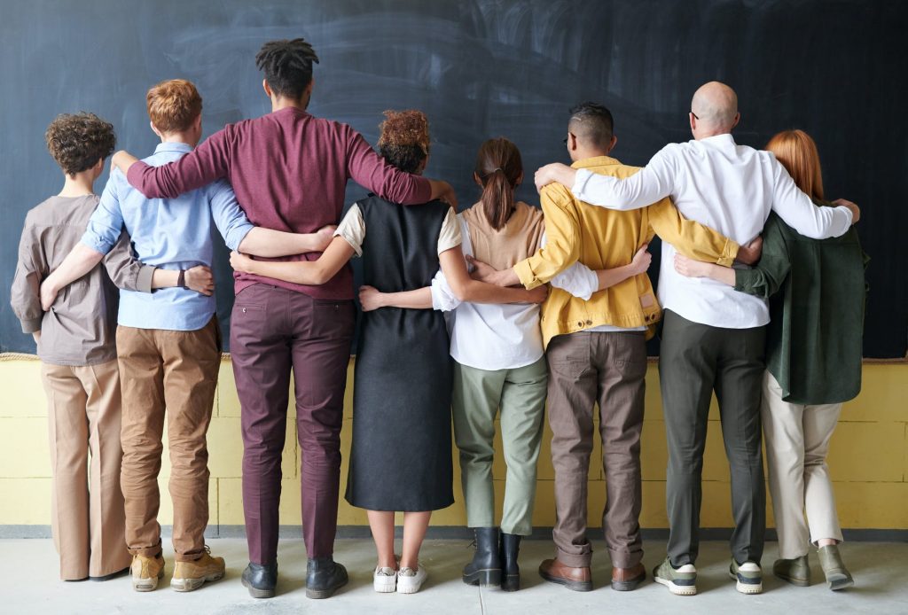 A group of people facing a wall with their arms around each other - a case study of diversity