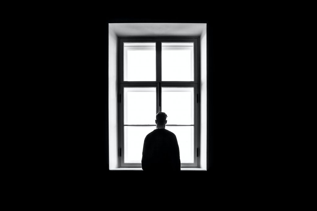 a person looks out a window in the dark.